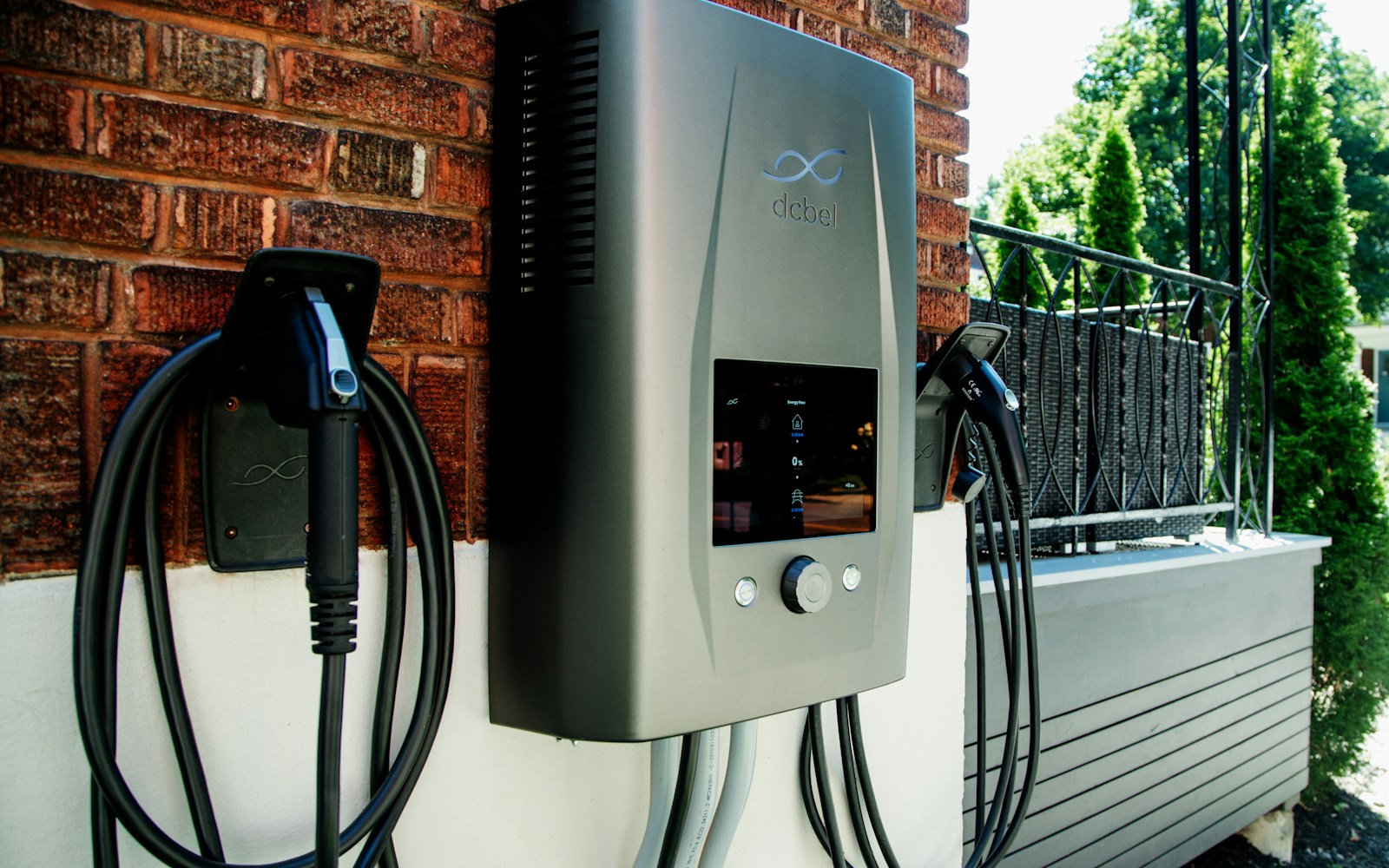 Wall-mounted electric vehicle charging unit beside a garage
